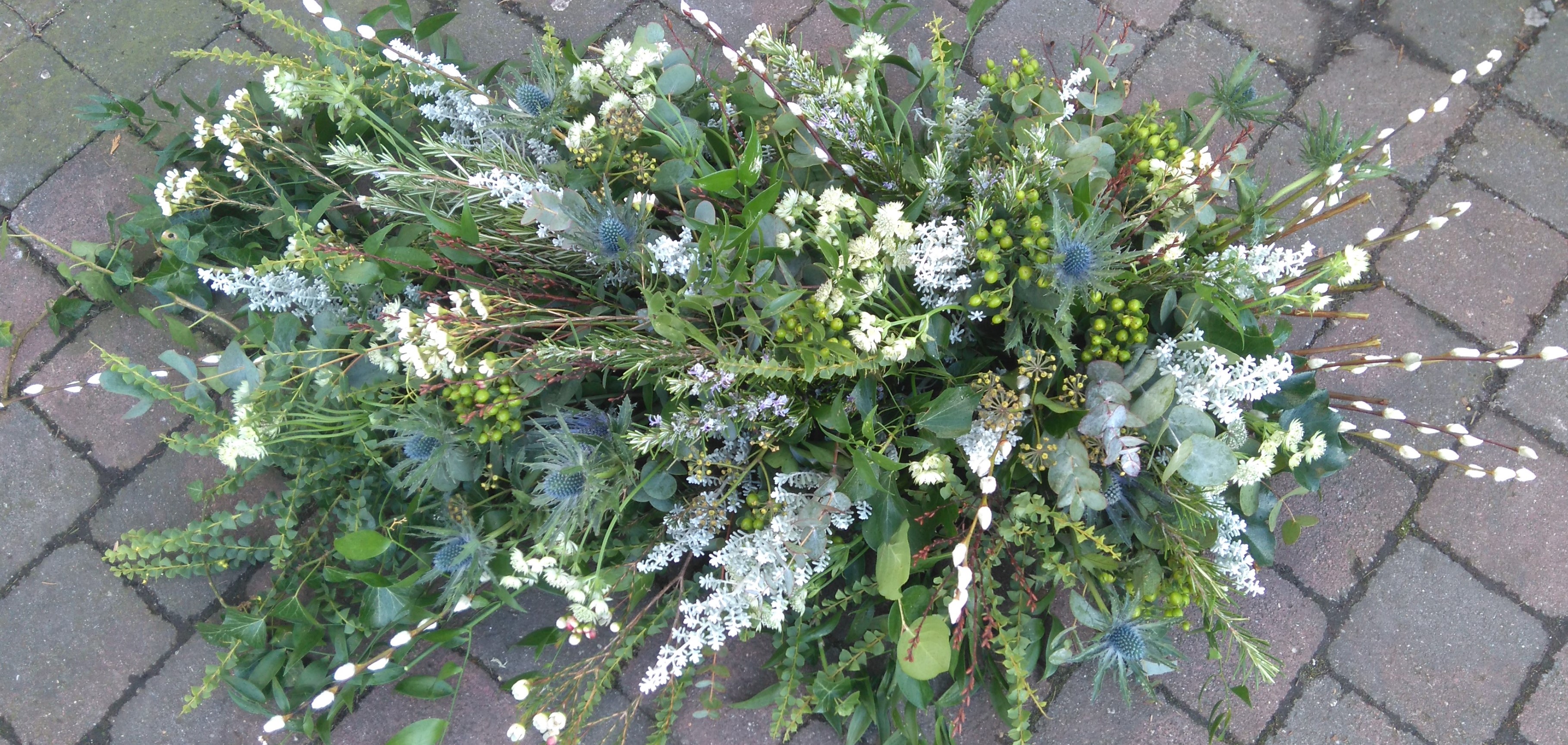 A wild, garden-style green and white casket spray by Blossom Flowers